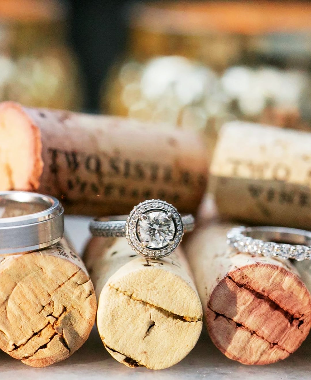 Close-up of wedding rings placed on wine corks, with a sparkling diamond engagement ring and wedding band displayed prominently