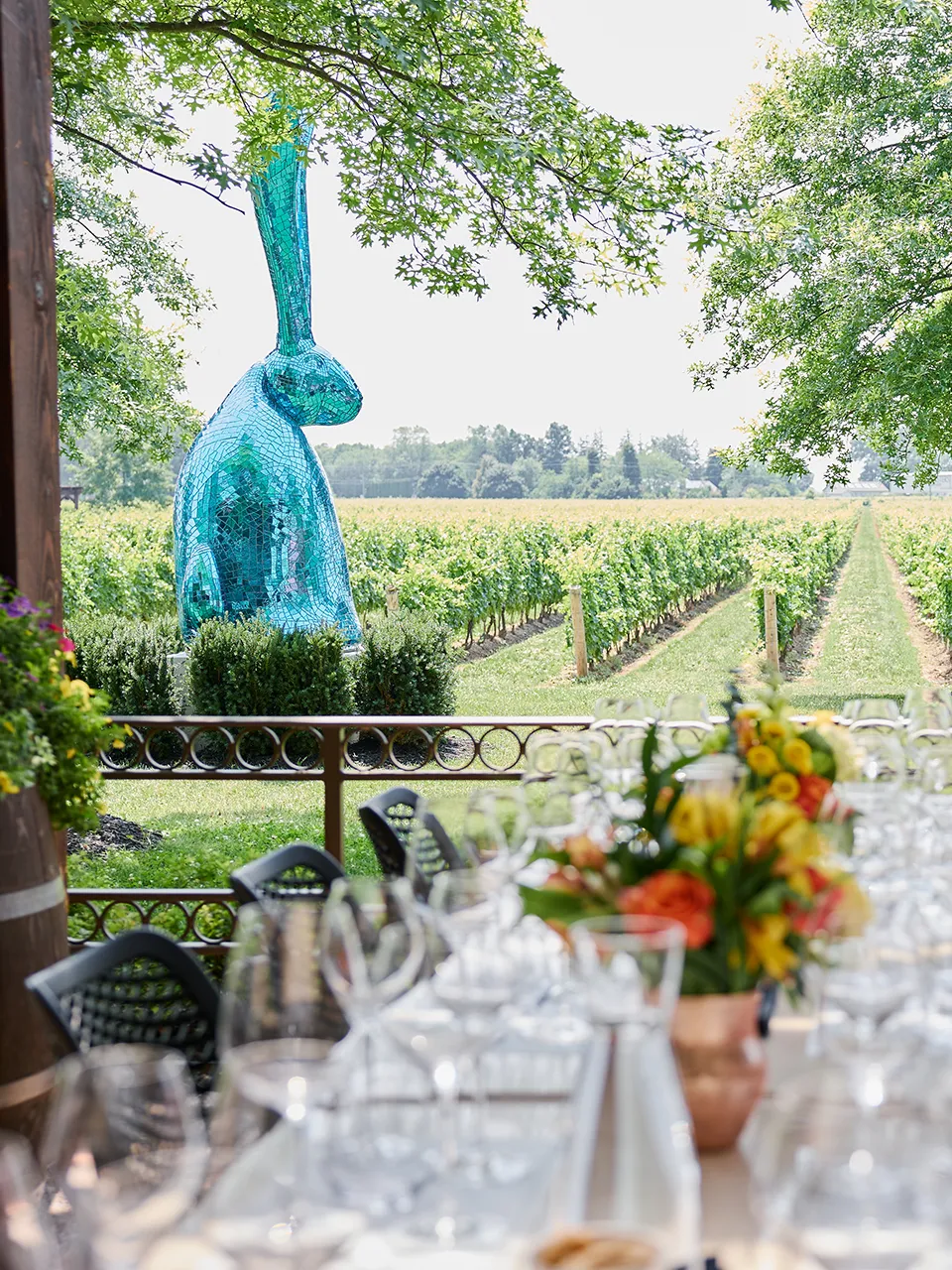 Elegant outdoor vineyard table setting with floral centerpieces, wine glasses, and place settings prepared for a summer event