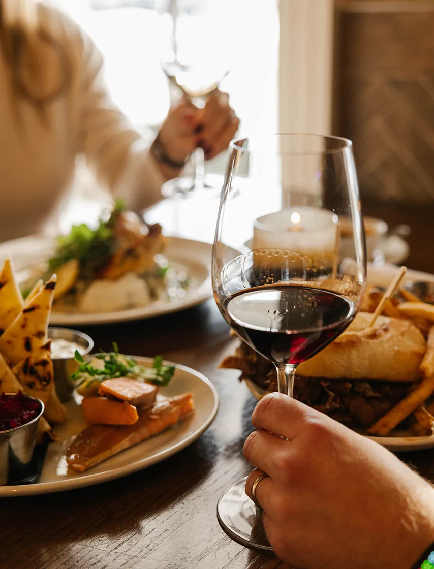 Dining at 11th Post On Queen, person holding a glass of red wine.